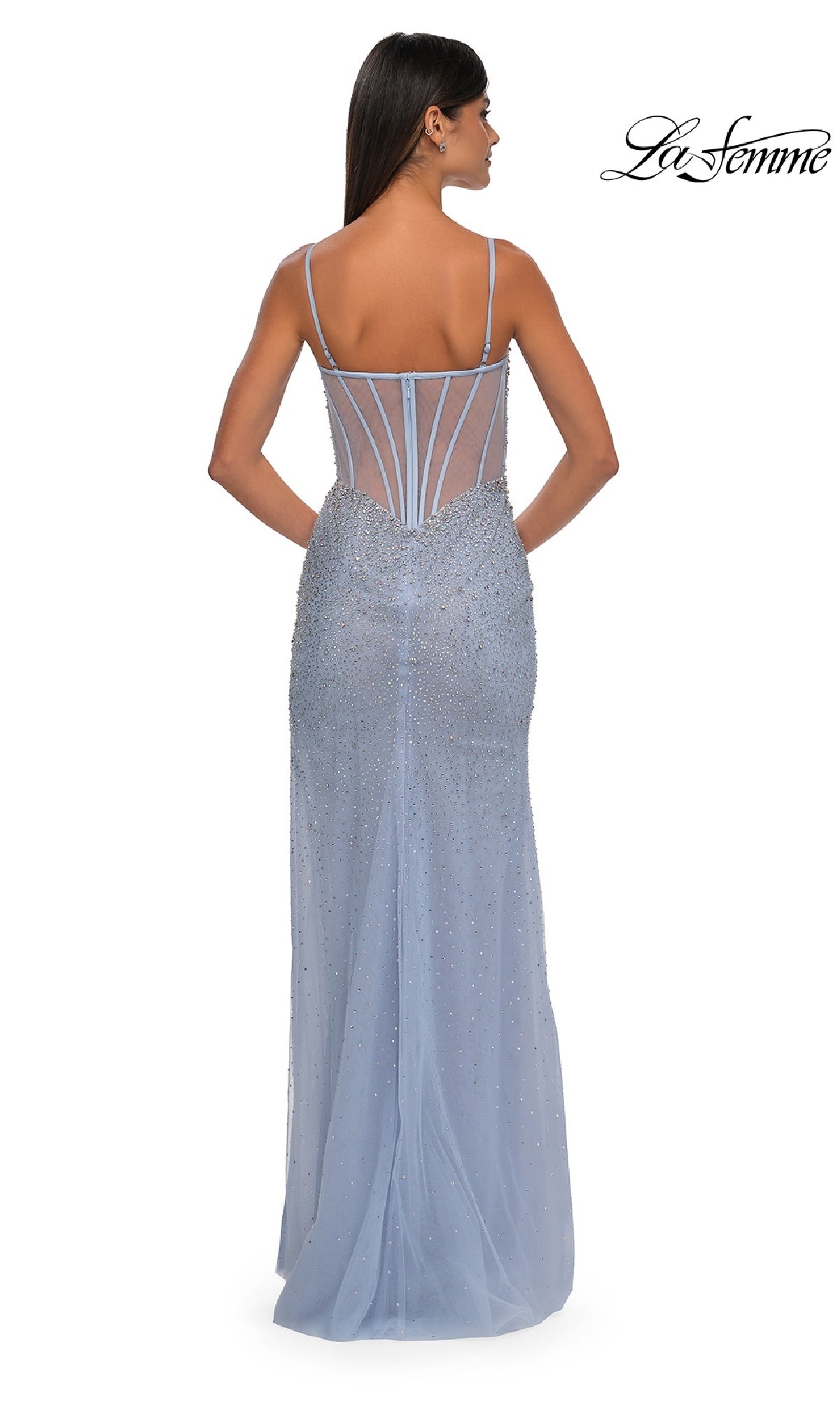 A woman faces away from the camera in the Long Beaded Prom Dress: La Femme 32840, a light blue gown with thin straps, sheer back paneling, and sparkling beaded embellishments.